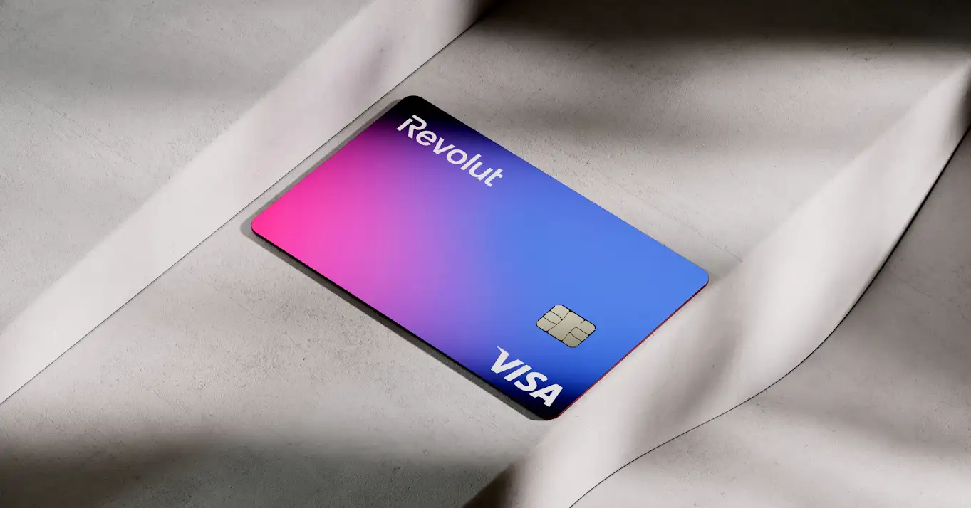 Cartão Revolut Visa em tons de azul e rosa sobre superfície clara.