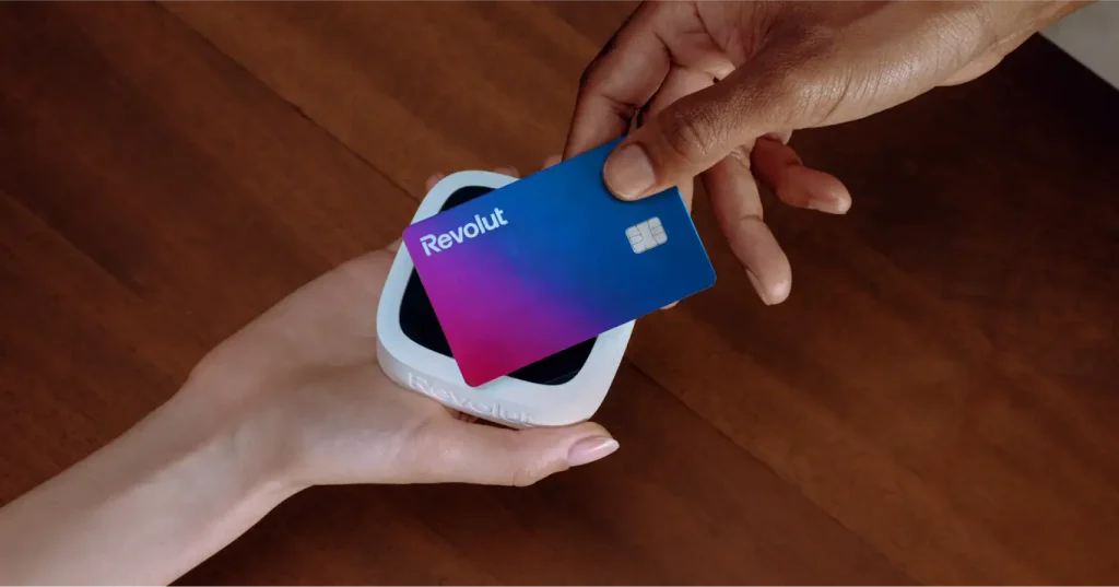 Pessoa aproximando um cartão Revolut de uma maquininha de pagamento.