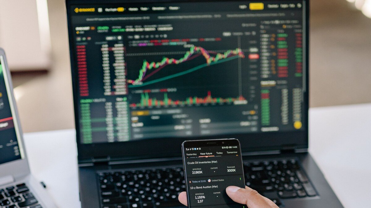 Pessoa acompanhando investimentos em ETFs pelo notebook e celular